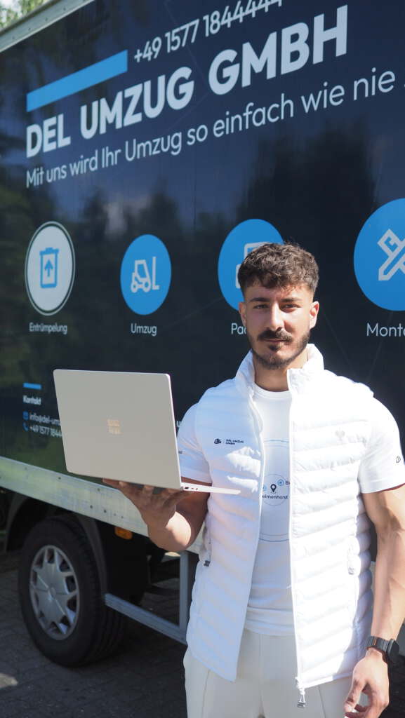 DEL UMZUG Ansprechpartner mit Laptop vor dem beschrifteten Firmenfahrzeug